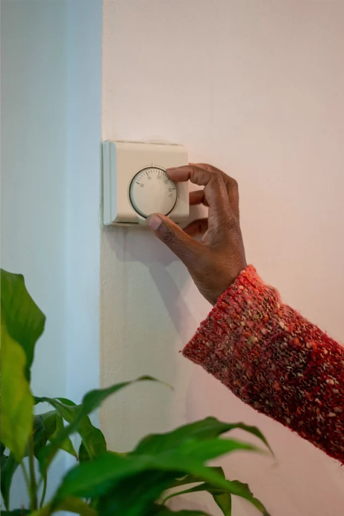 Personne ajustant un thermostat dans un bureau, illustrant l'importance des gestes quotidiens pour économiser l'énergie.