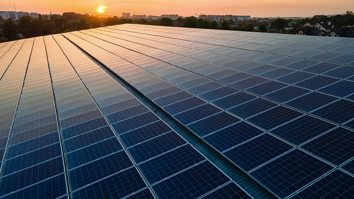 Coucher de soleil sur une grande installation de panneaux solaires, symbolisant la transition énergétique.